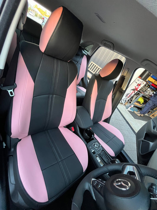 Close-up view of front seats in a Mazda CX-3 with custom light pink and black artificial Nappa leather seat covers
