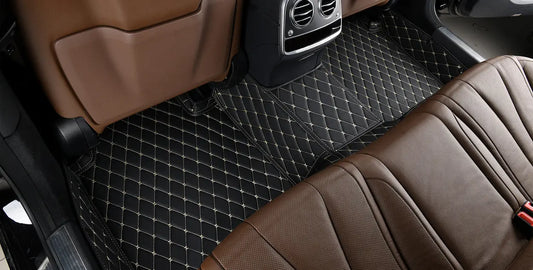 view of beautiful black luxury floor mats installed in the back of a car, contrasted with brown leather interior